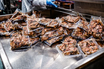 Sealed packages of cooked meat or protein on stainless steel preparation surface