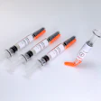 Five medical syringes with orange safety caps on white background
