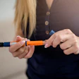 Orange and blue medical auto-injector held in hands
