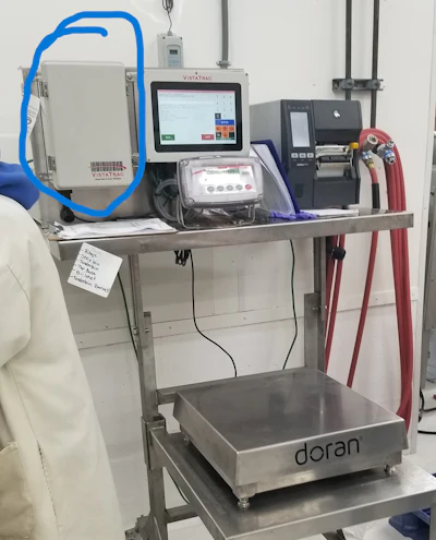 Laboratory workbench with medical diagnostic equipment including VistaTraC analyzer, Doran scale, and various monitoring devices with blue tubing and red cables.