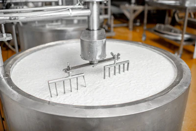 Large stainless steel industrial mixing tank with rake-style agitators in a food processing facility