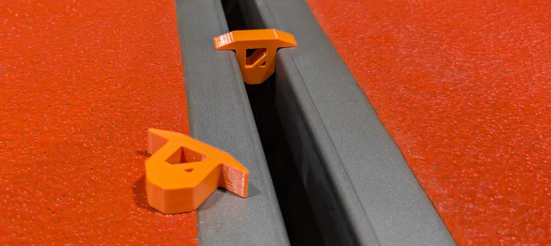 Orange plastic fasteners and clips mounted on gray metal channel track