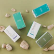 Curology skincare products arranged with pumice stones on sage green background