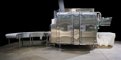 Industrial stainless steel sterilization or processing chamber with conveyor systems and control equipment on concrete floor