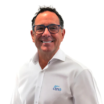 Professional man wearing glasses and white TNA-branded shirt, smiling against white background