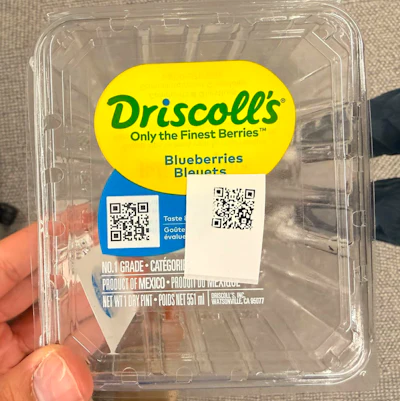 A Driscoll's blueberry clamshell carrying two QR codes &mdash; one pre-printed on the brand label, one applied at the farm. Together they're central to a serialization program that has given more than a billion packages a unique, traceable identity.