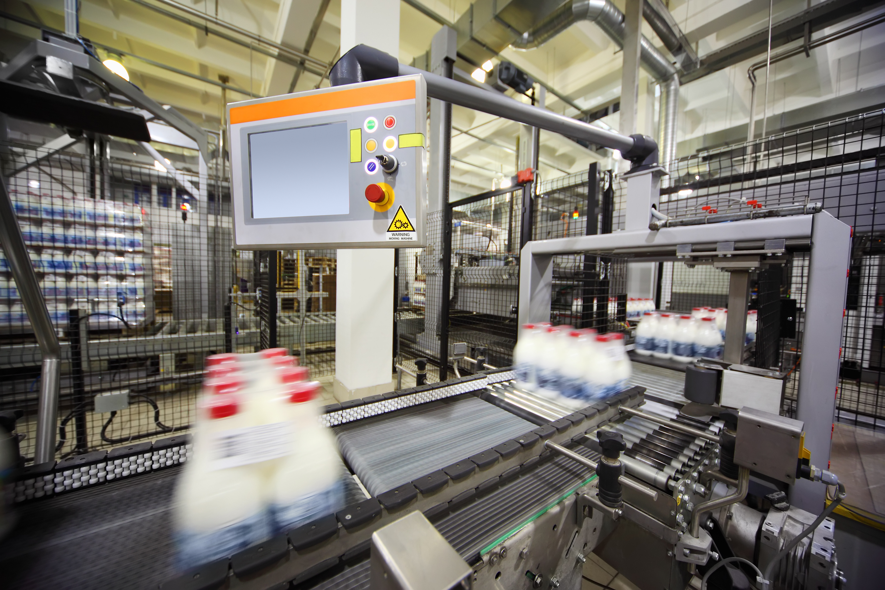 Industrial automated packaging machinery with conveyor systems and control panel in manufacturing facility