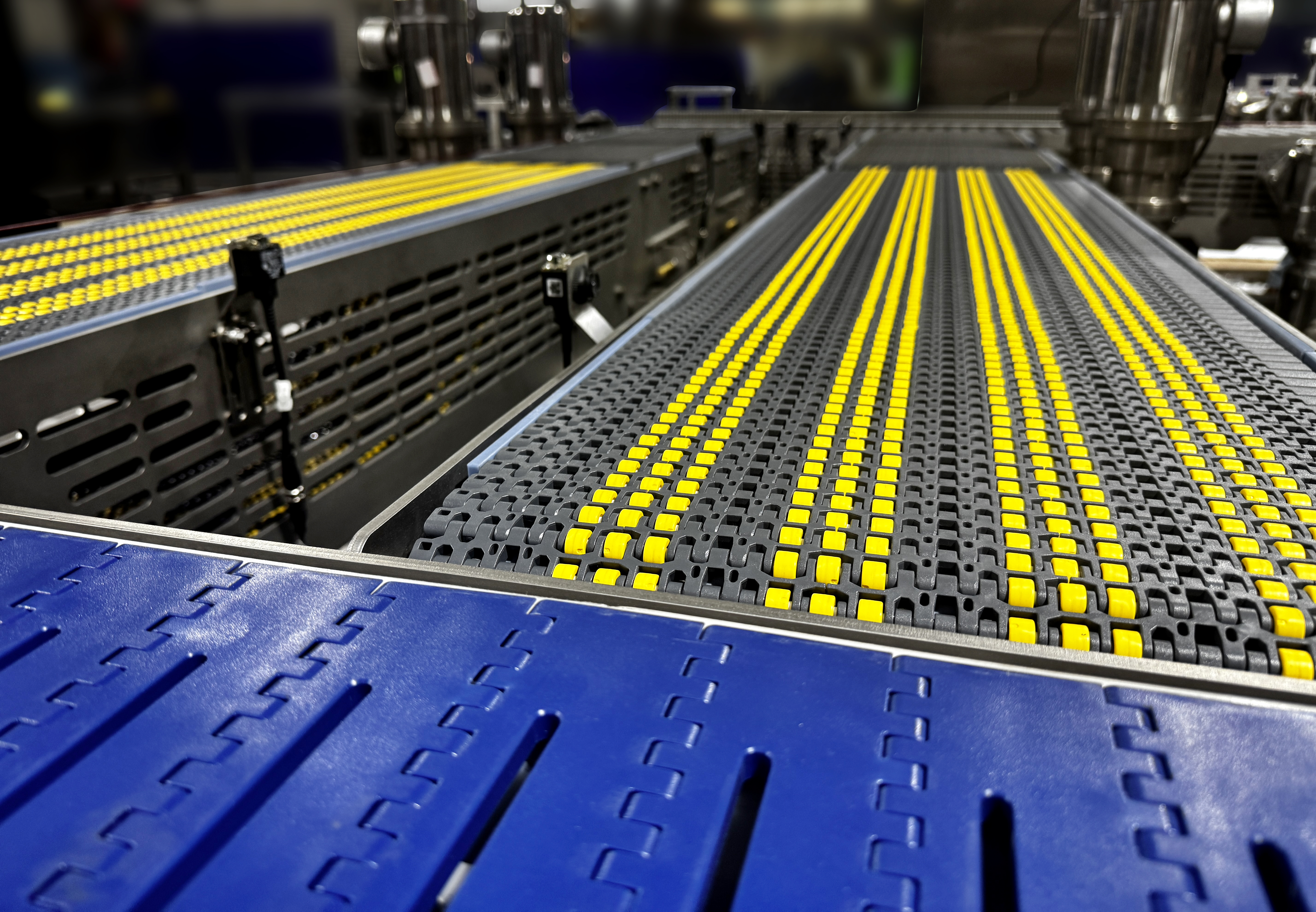 Industrial conveyor belt system with yellow and gray modular components in a manufacturing facility