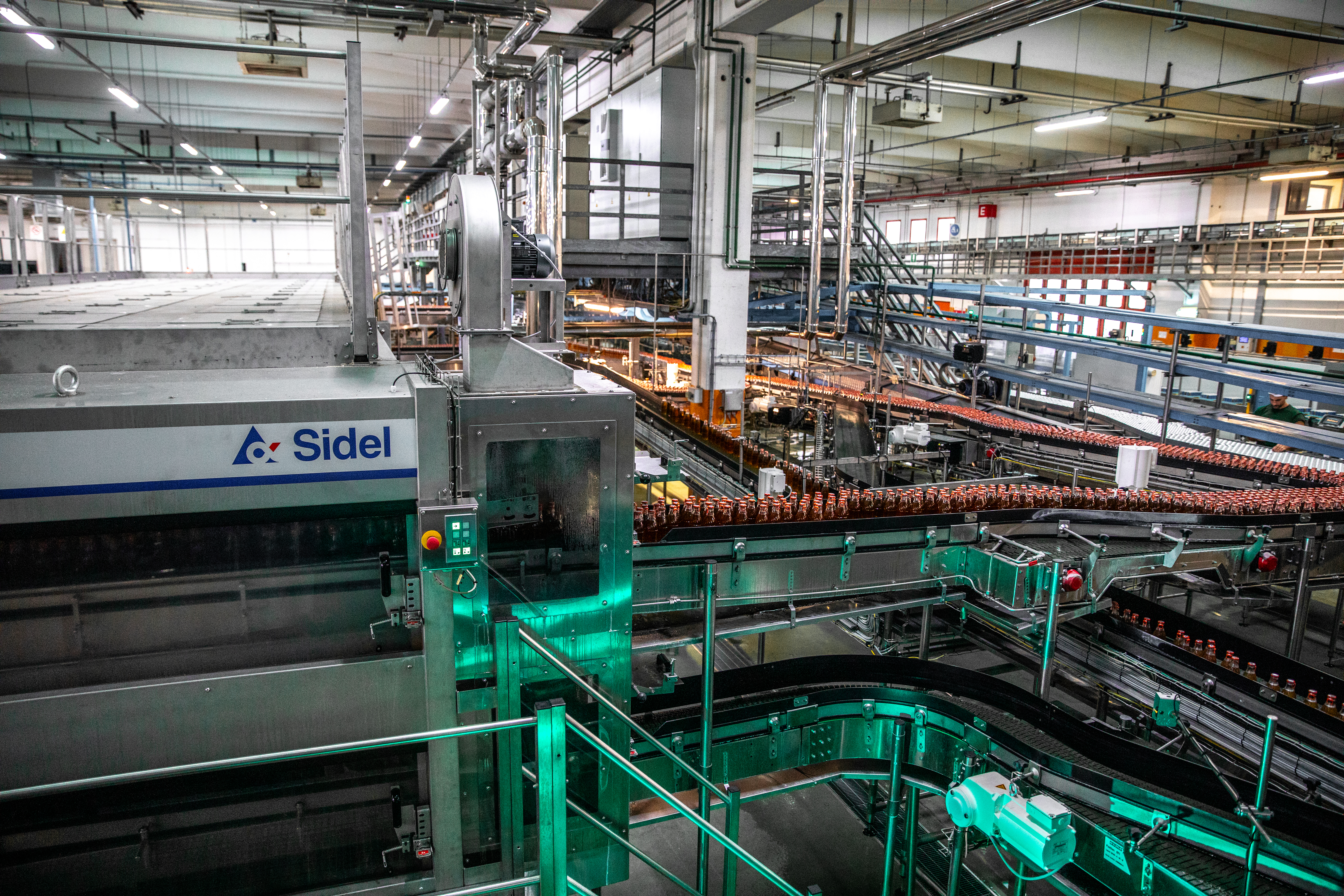 Industrial beverage bottling facility with Sidel machinery and conveyor systems processing bottles on production lines