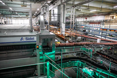 Industrial beverage bottling facility with Sidel machinery and conveyor systems processing bottles on production lines