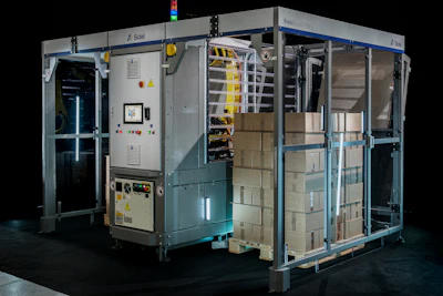 Industrial automated packaging machine with blue frame, control panels, and cardboard boxes on conveyor system