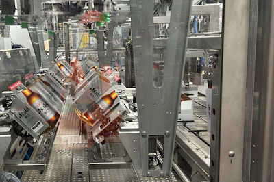 Eight paperboard carriers at a time are picked from magazine feeds and erected so that they can be picked and placed into corrugated cases that can be seen on the right.
