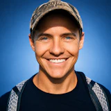 Smiling man wearing a distressed baseball cap and dark shirt against blue background