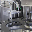 Multi-head 3D printer with metal frame, white tubing, and black build platform in laboratory setting