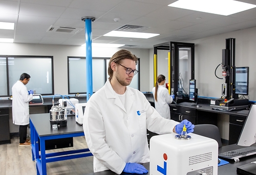 Scientist in white lab coat working with 3D printer equipment in modern laboratory facility