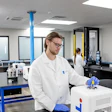 Scientist in white lab coat working with 3D printer equipment in modern laboratory facility