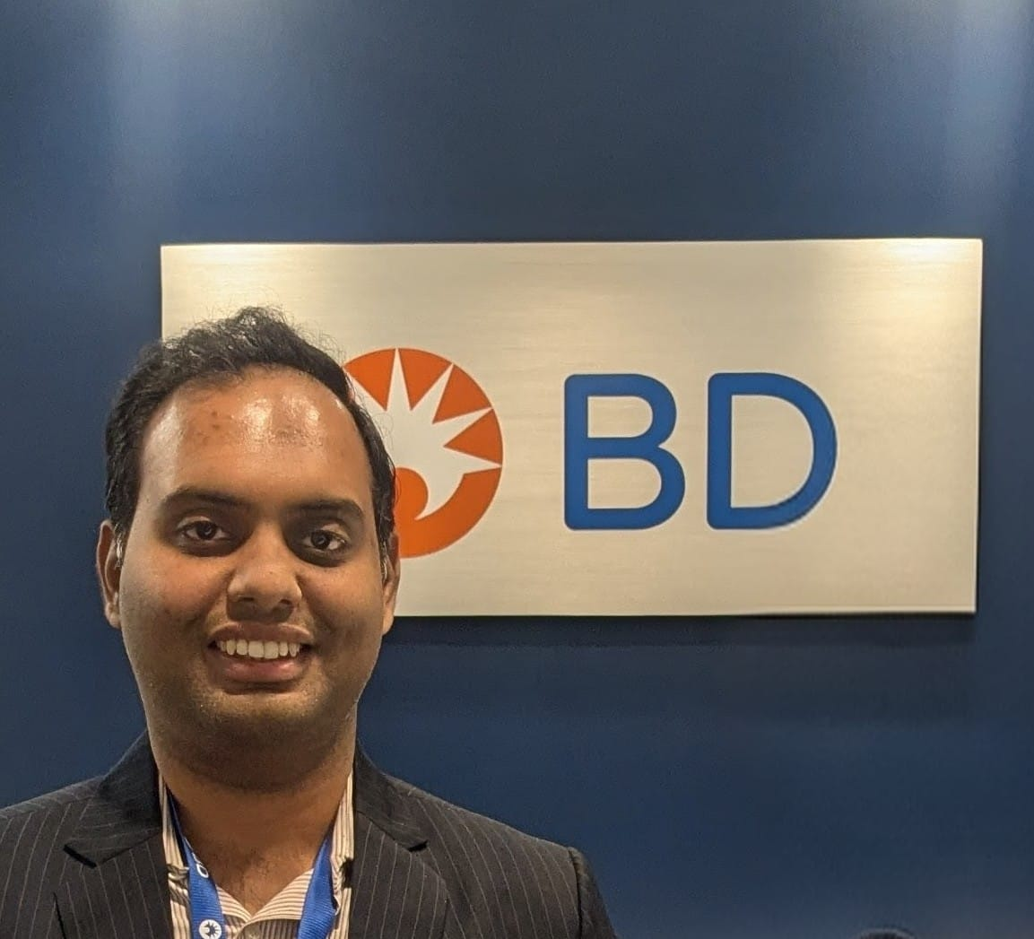 Professional man smiling at BD corporate event or office with company logo signage in background