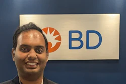 Professional man smiling at BD corporate event or office with company logo signage in background