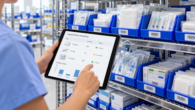 Worker holding tablet displaying supply room inventory dashboard with charts in front of blue storage bins