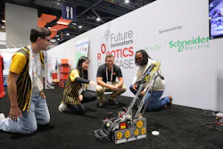 Team members demonstrate a yellow and black robot at the Future Innovators Robotics Showcase, sponsored by Schneider Electric.