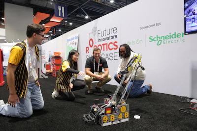 Team members demonstrate a yellow and black robot at the Future Innovators Robotics Showcase, sponsored by Schneider Electric.