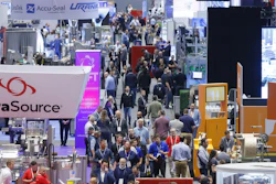 Busy trade show exhibition floor with multiple vendor booths, attendees in business attire, and corporate signage including DataSource, Accu-Seal, and Urani branding.