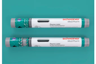 Two Schreiner MediPharm Pharma-Label tubes for pens and autoinjectors with green patterned sleeves on turquoise background
