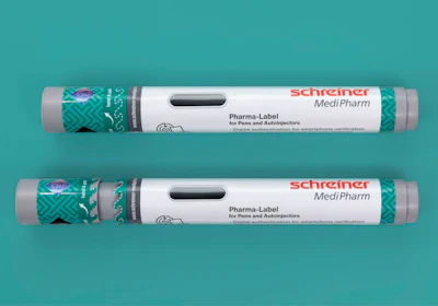 Two Schreiner MediPharm Pharma-Label tubes for pens and autoinjectors with green patterned sleeves on turquoise background